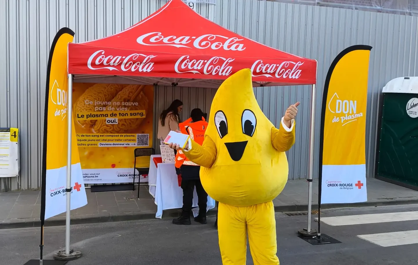 Mascotte Plasma devant un stand de don de sang de la Croix-Rouge