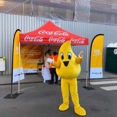 Mascotte Plasma devant un stand de don de sang de la Croix-Rouge